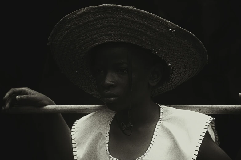 woman in large straw hat holding onto bar to camera