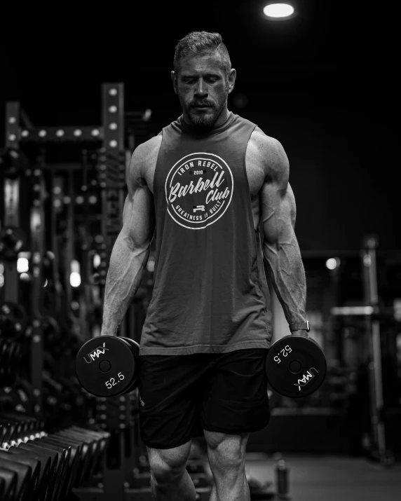 a male in a gray shirt and black shorts and with dumbbells