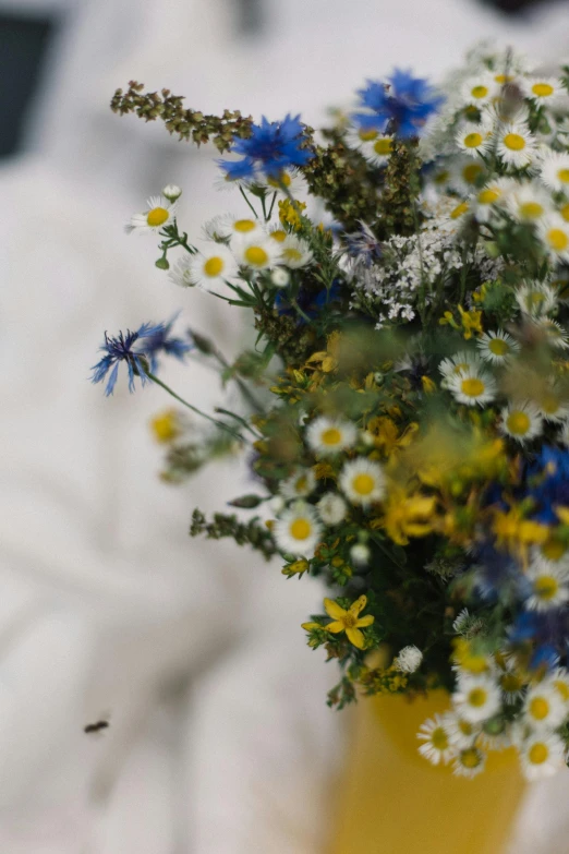 a yellow vase with many blue and yellow flowers