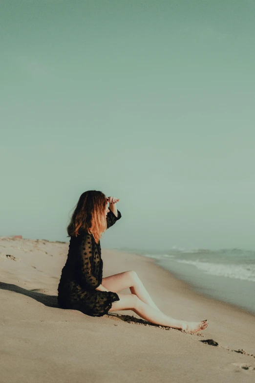 a young woman sitting on top of a sandy beach