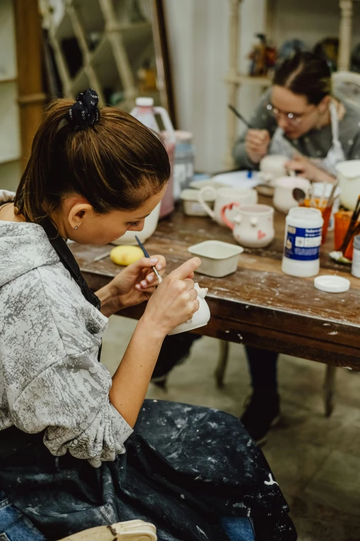 woman sitting at table with some jars of paint and fruit