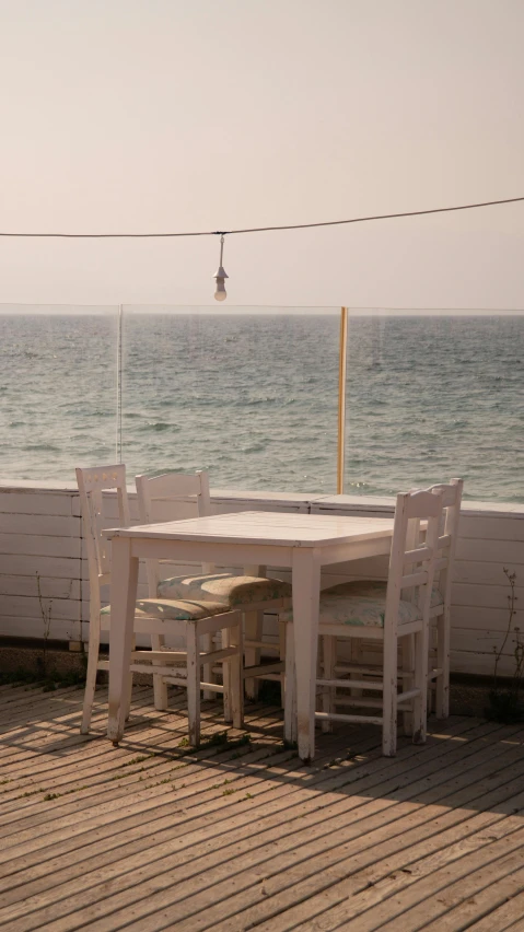 a table and four chairs are outside near the water