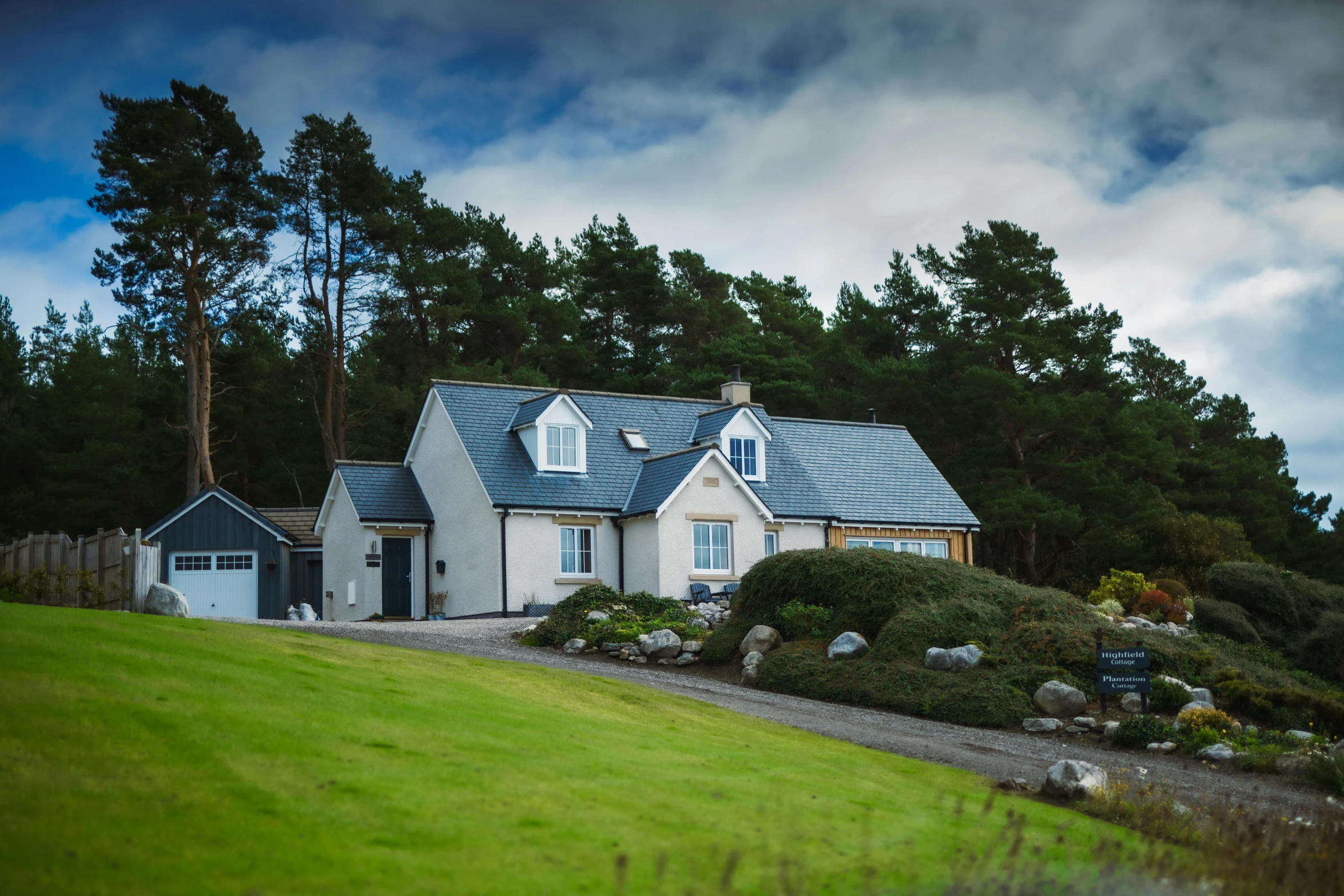 a white and gray house with blue roof and door and grass next to it