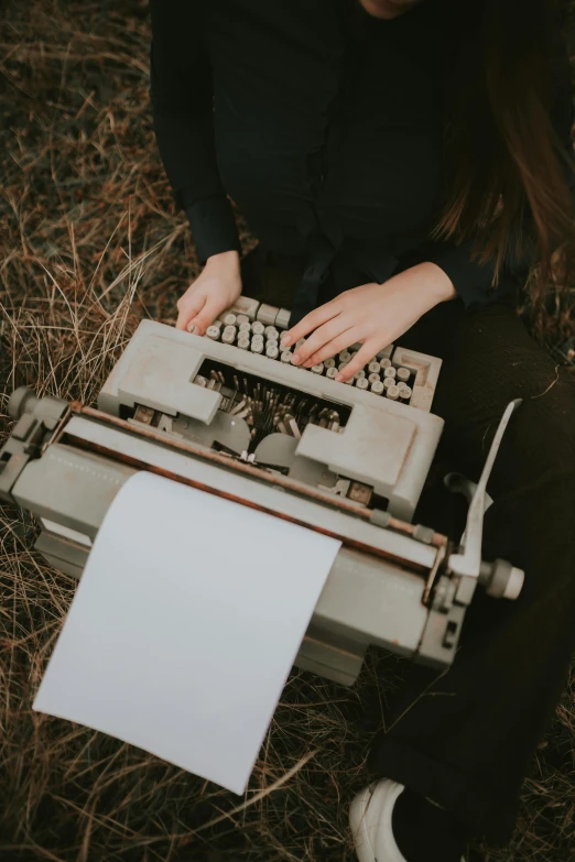 a woman sits next to an old, broken typewriter