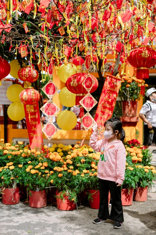 a little girl standing under the chinese lanterns