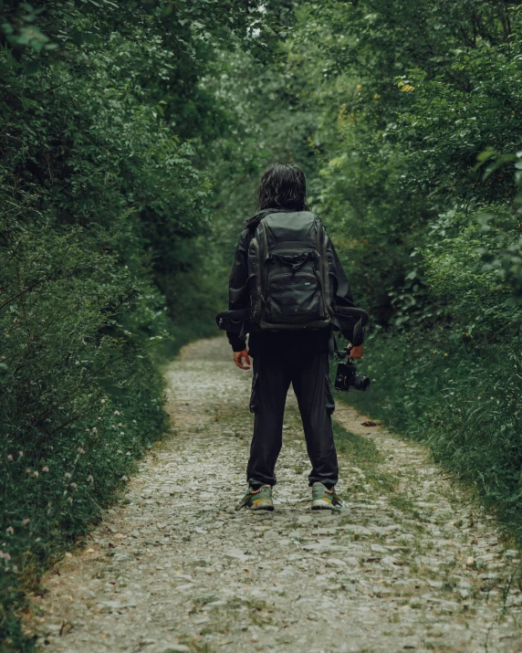 a person with a backpack is walking down a dirt path