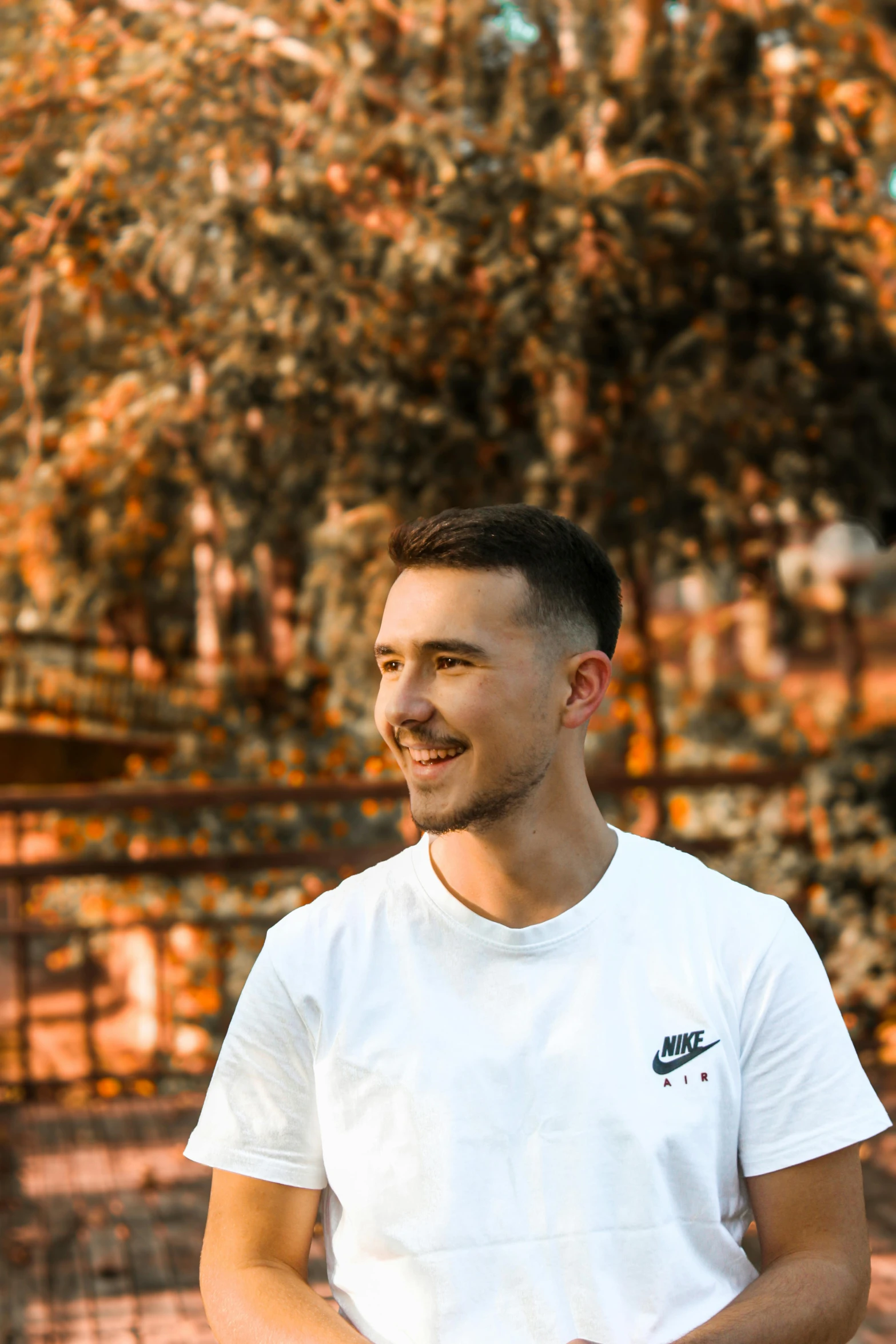 the man is smiling as he poses in front of a tree