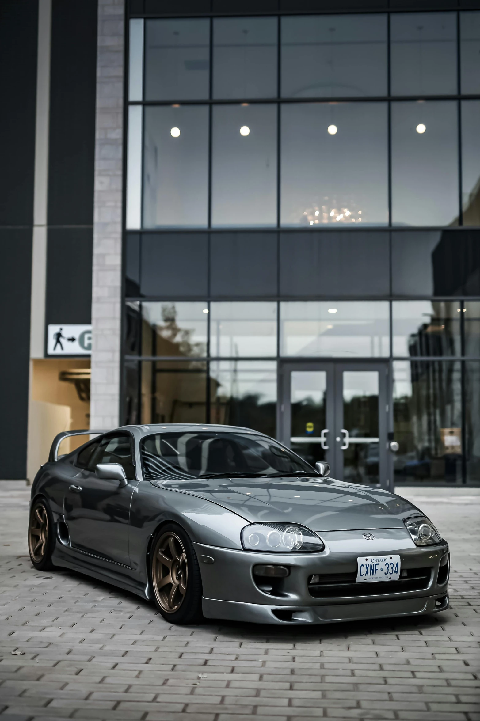 a silver sports car parked outside of a glass building