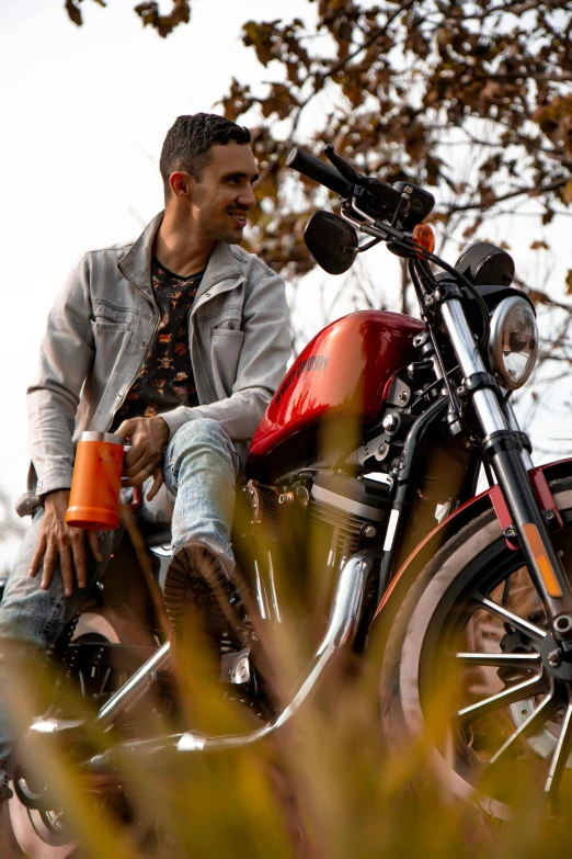 a young man sitting on top of a red motorcycle