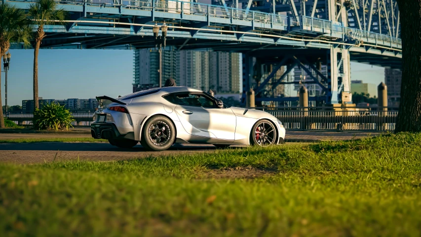 a mercedes benz sports car is parked in front of a park under a bridge