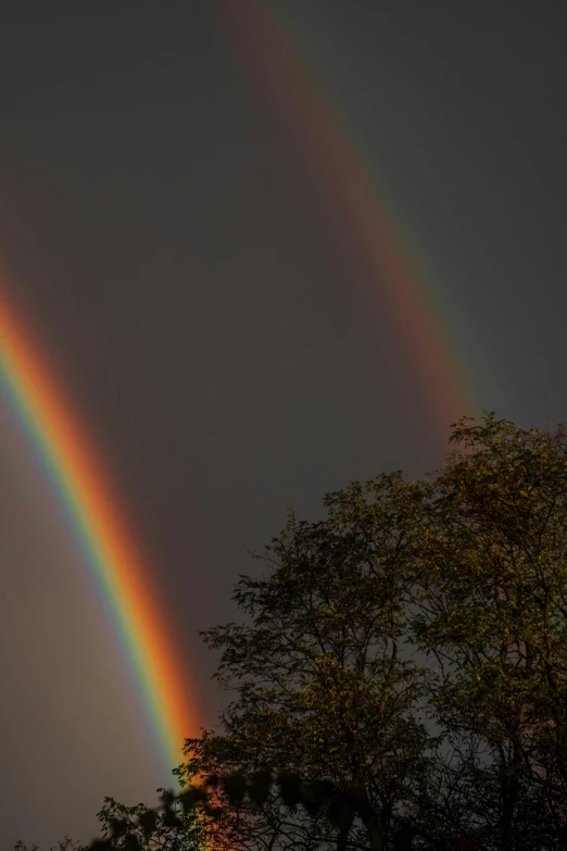 the double rainbow shines brightly against the dark sky