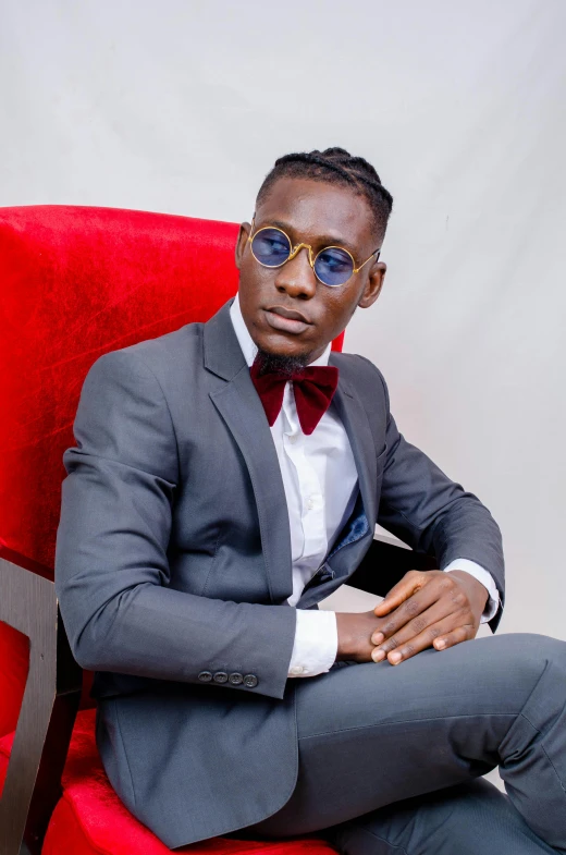 a black man sitting in a red chair wearing sunglasses