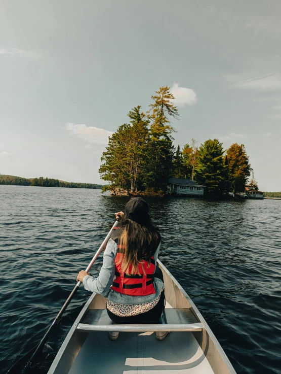 two people paddling on a canoe, one holding a paddle and the other facing back in an overcast day