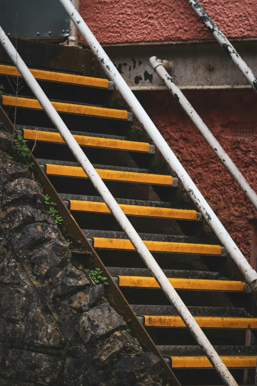 an industrial stair case with yellow steps against a red wall