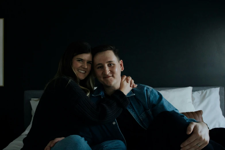 man and woman cuddling on a bed at night