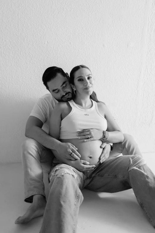 a pregnant man and woman sitting on the floor together