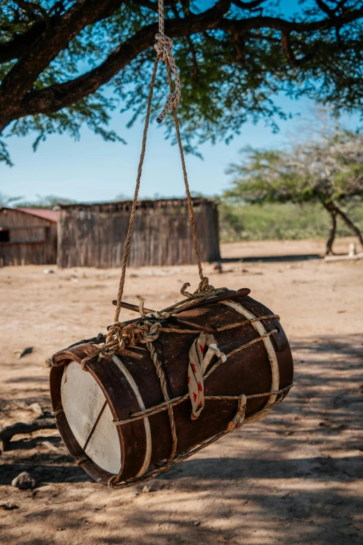 a drum hanging on a rope between two trees