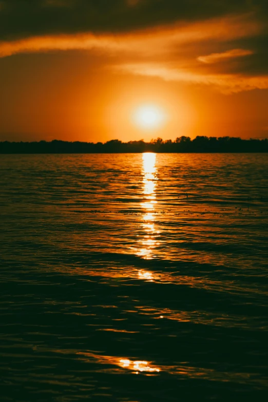 the sun setting over water with dark clouds