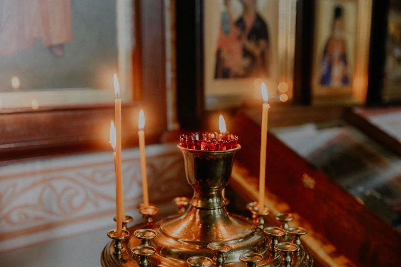 three candles on a golden stand with a red candle