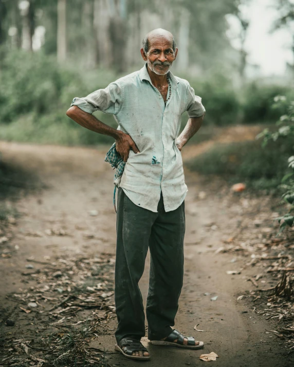 an elderly man stands in the middle of a wooded trail