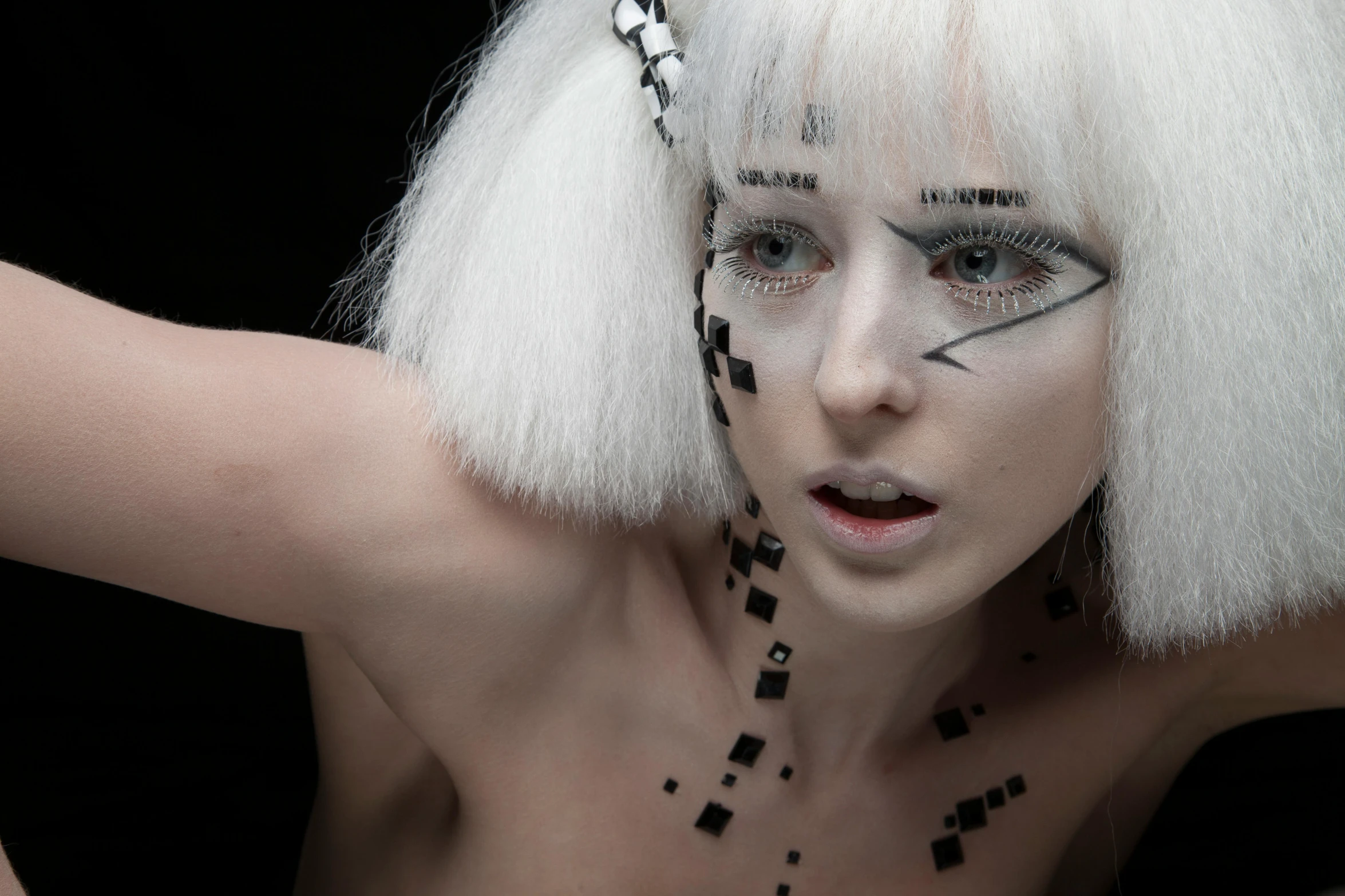 a model with white hair has geometric makeup