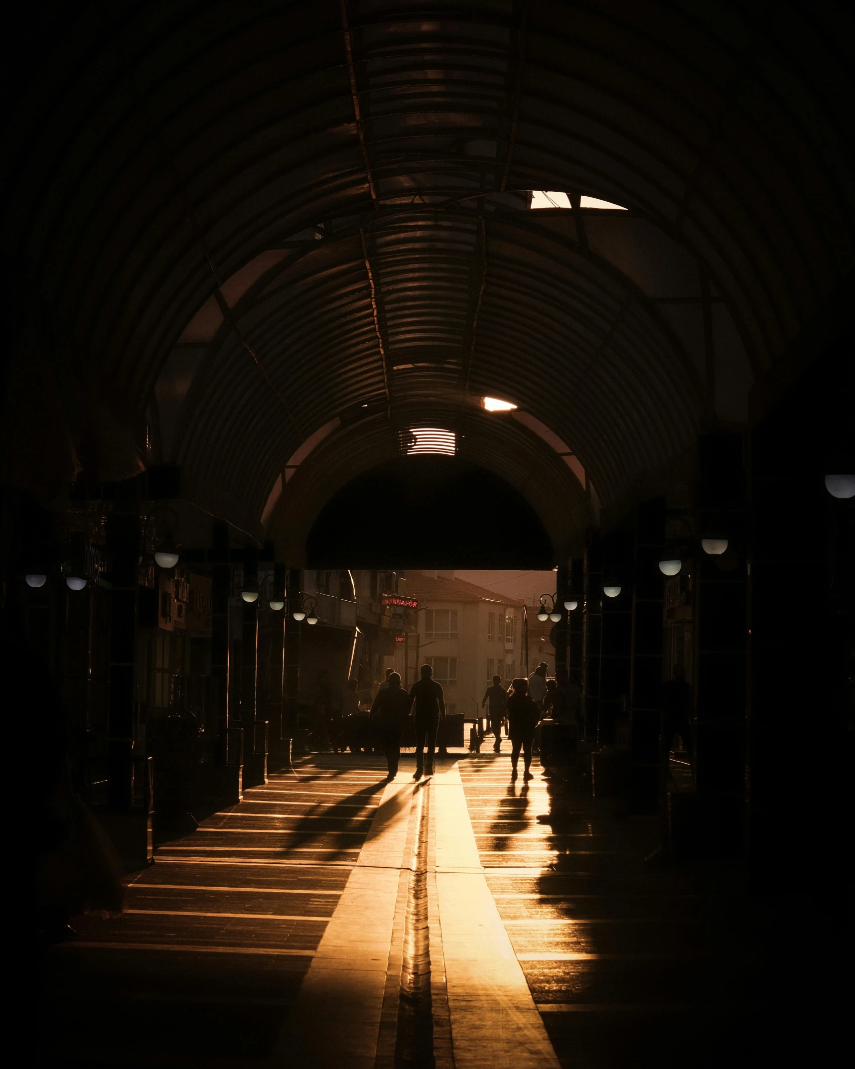 people walk down the tunnel between trains in darkness