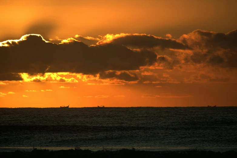 an orange sunset with some boats in the background