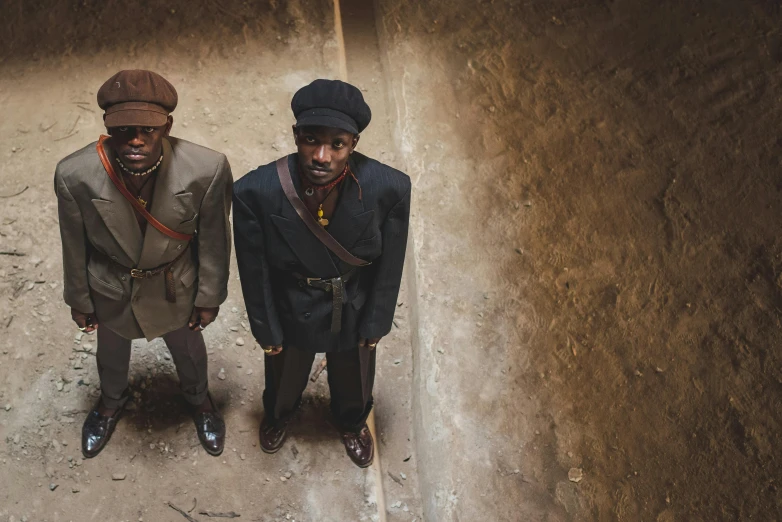 two men are sitting side by side wearing clothes