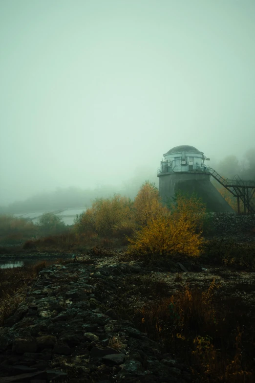 a train station that is in the fog near a river