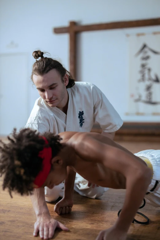 a man doing h ups on the ground with a woman behind him