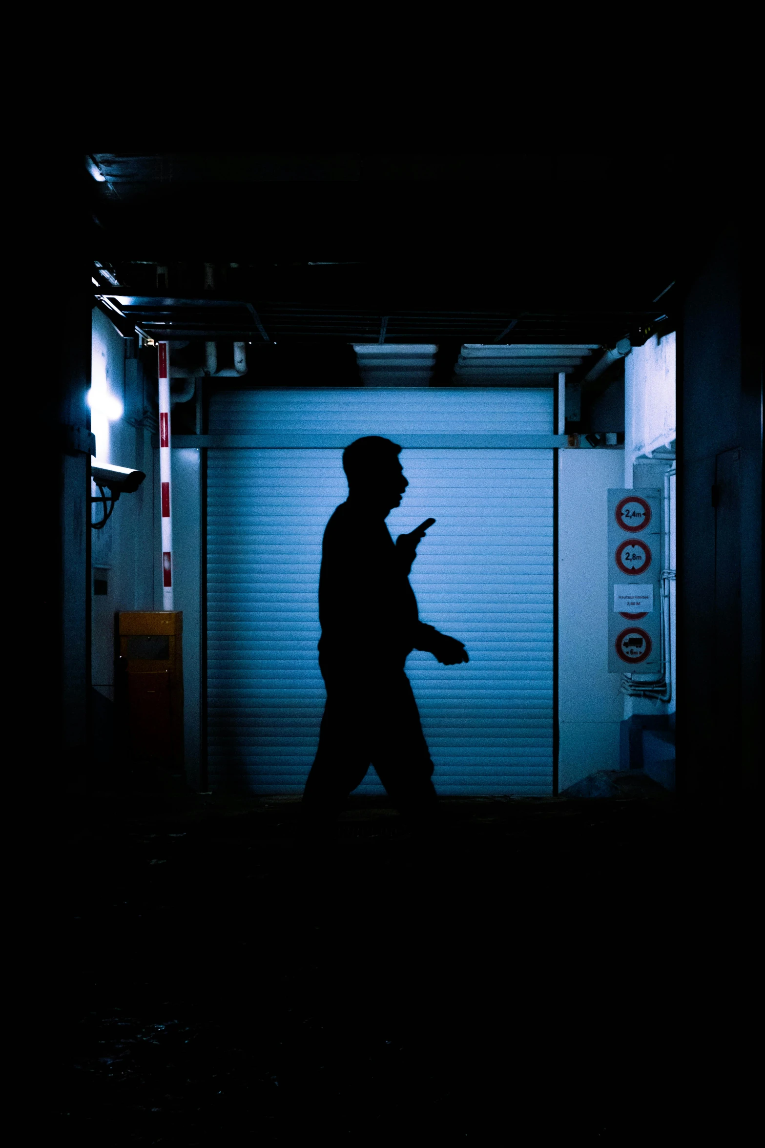 a man walks in a darkened doorway on his cell phone