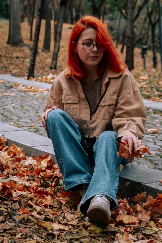 a woman with red hair sitting on a bench surrounded by leaves