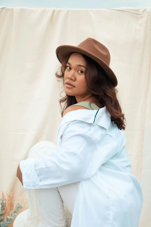 a woman in white is wearing a brown hat