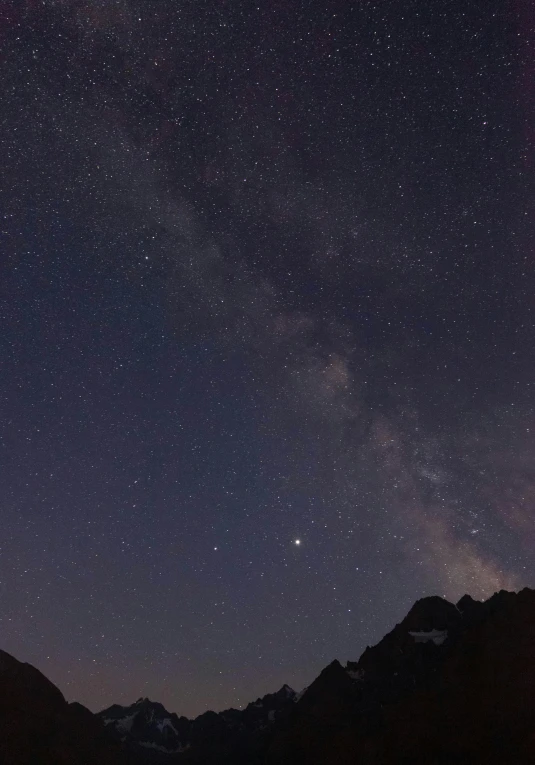 the night sky filled with stars and light reflecting off of mountains