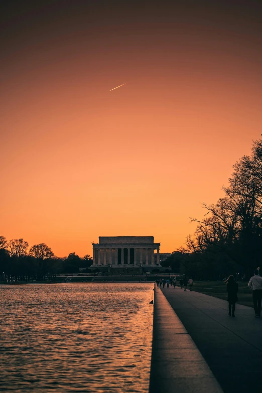 a view of the lincoln memorial at dusk with people walking by