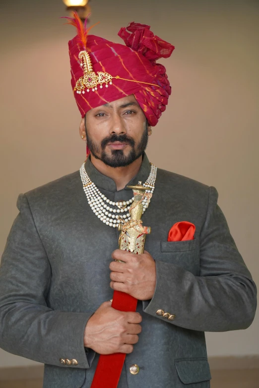 a man with a turban standing with a red object