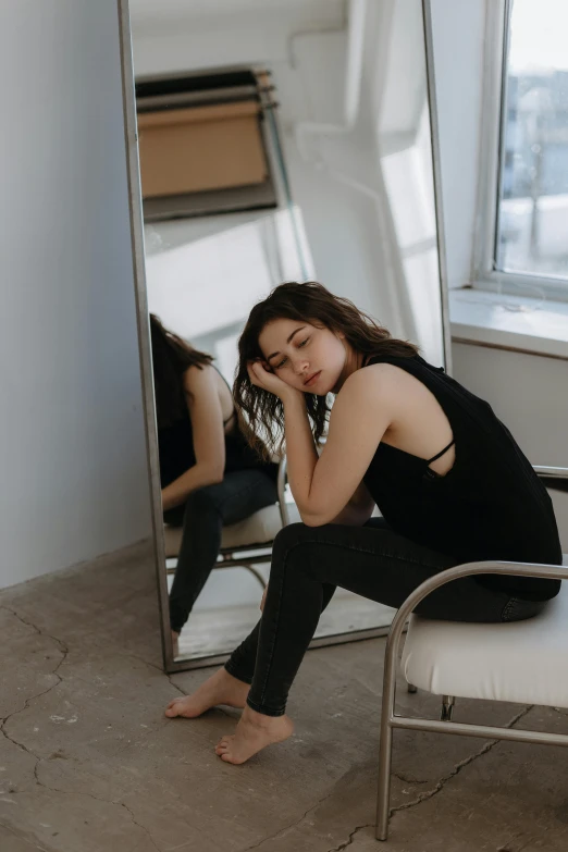 young woman looking in mirror leaning on bench