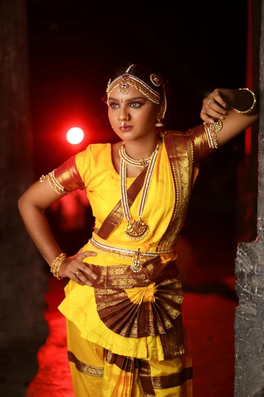 a woman in traditional attire stands with her hands on the hips