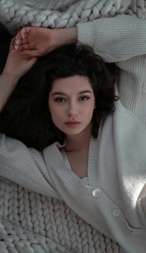 a woman is lying in a white sweater