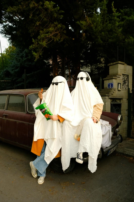 two people in white cloths are near a black car