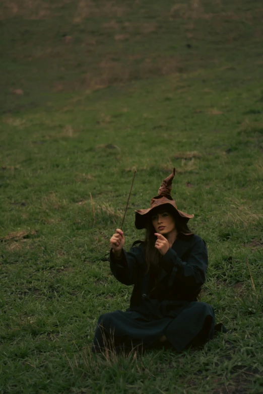 a little girl dressed up and holding two sticks