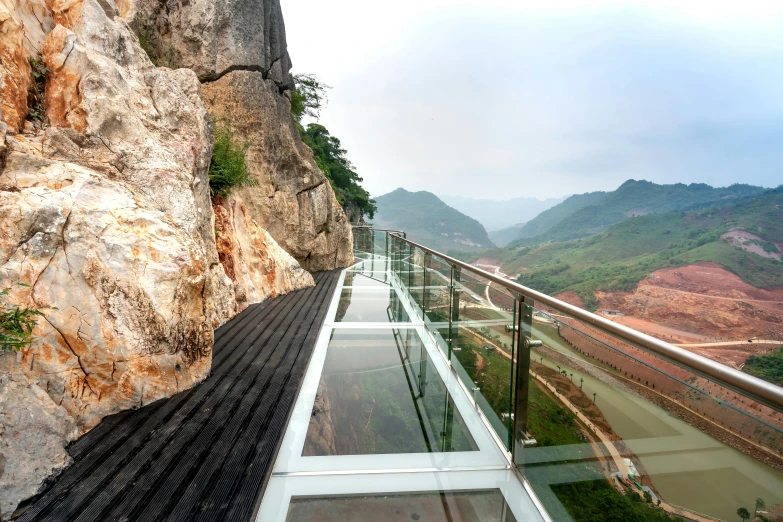 the walkway that runs beside an old waterfall in the mountain is made of glass