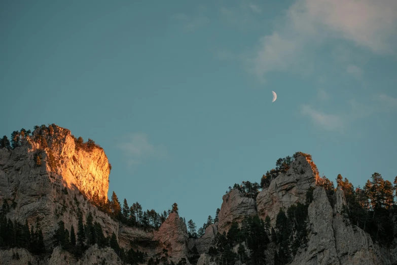 the moon is low and shining in the sky over mountains