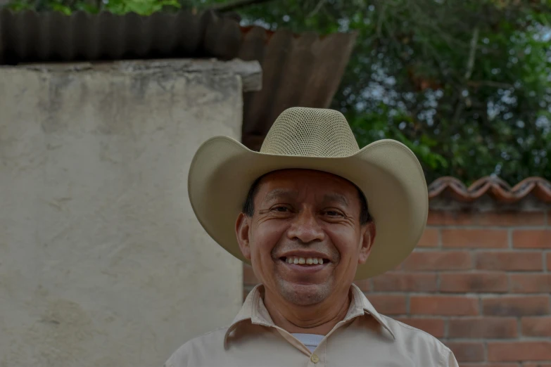 an older man wearing a cowboy hat smiling for the camera