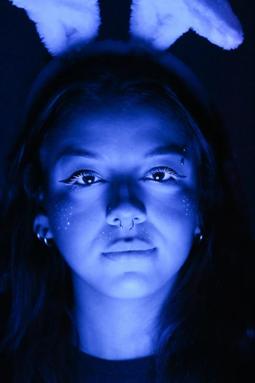 a woman wearing glowing blue bunny ears with snow on her forehead