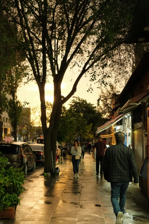 a man walks down a sidewalk with cars parked nearby