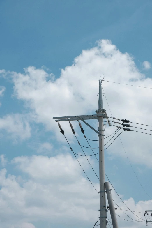 a very tall white light pole with wires attached to it