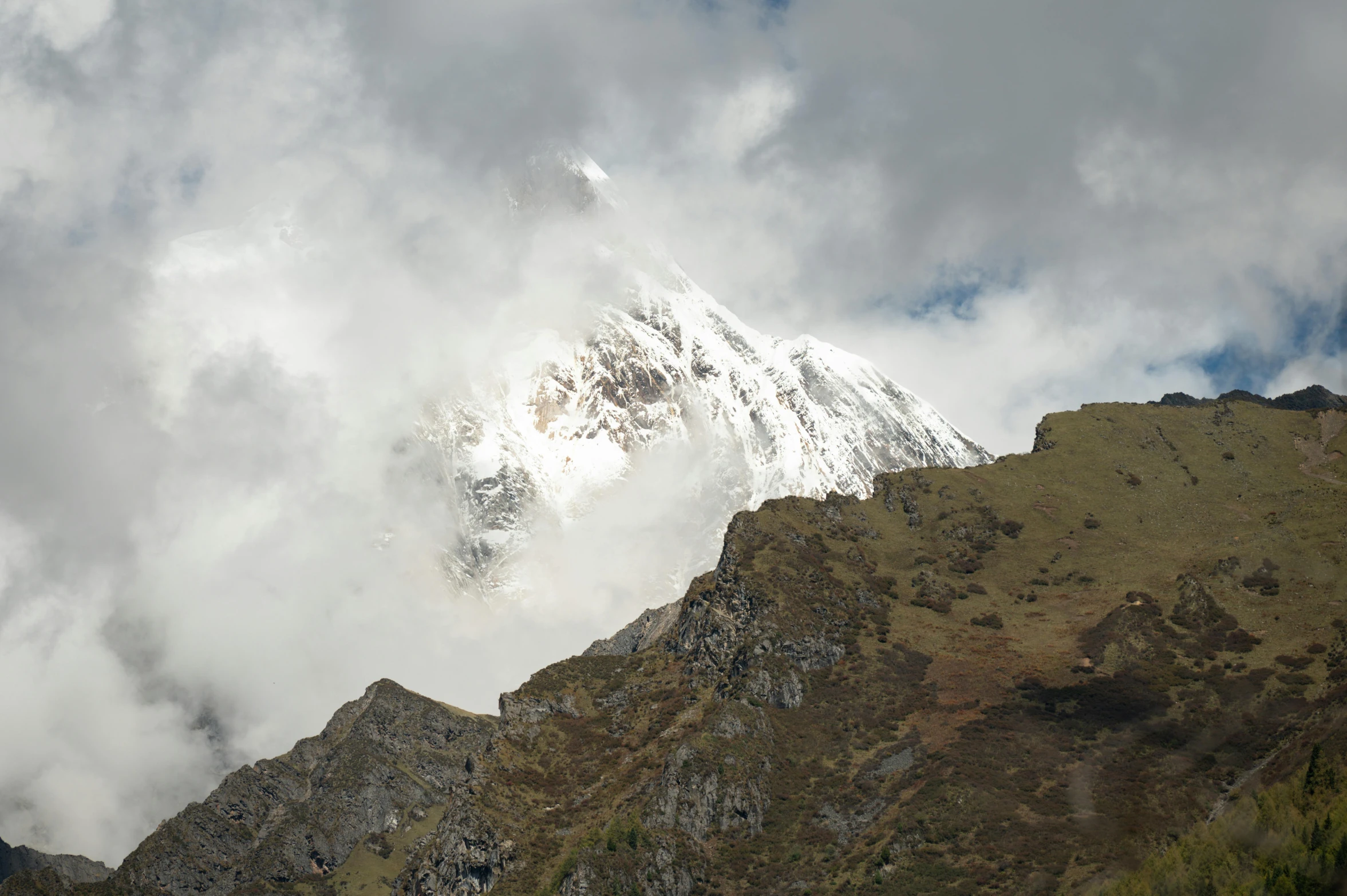 a mountain has clouds rolling in front it