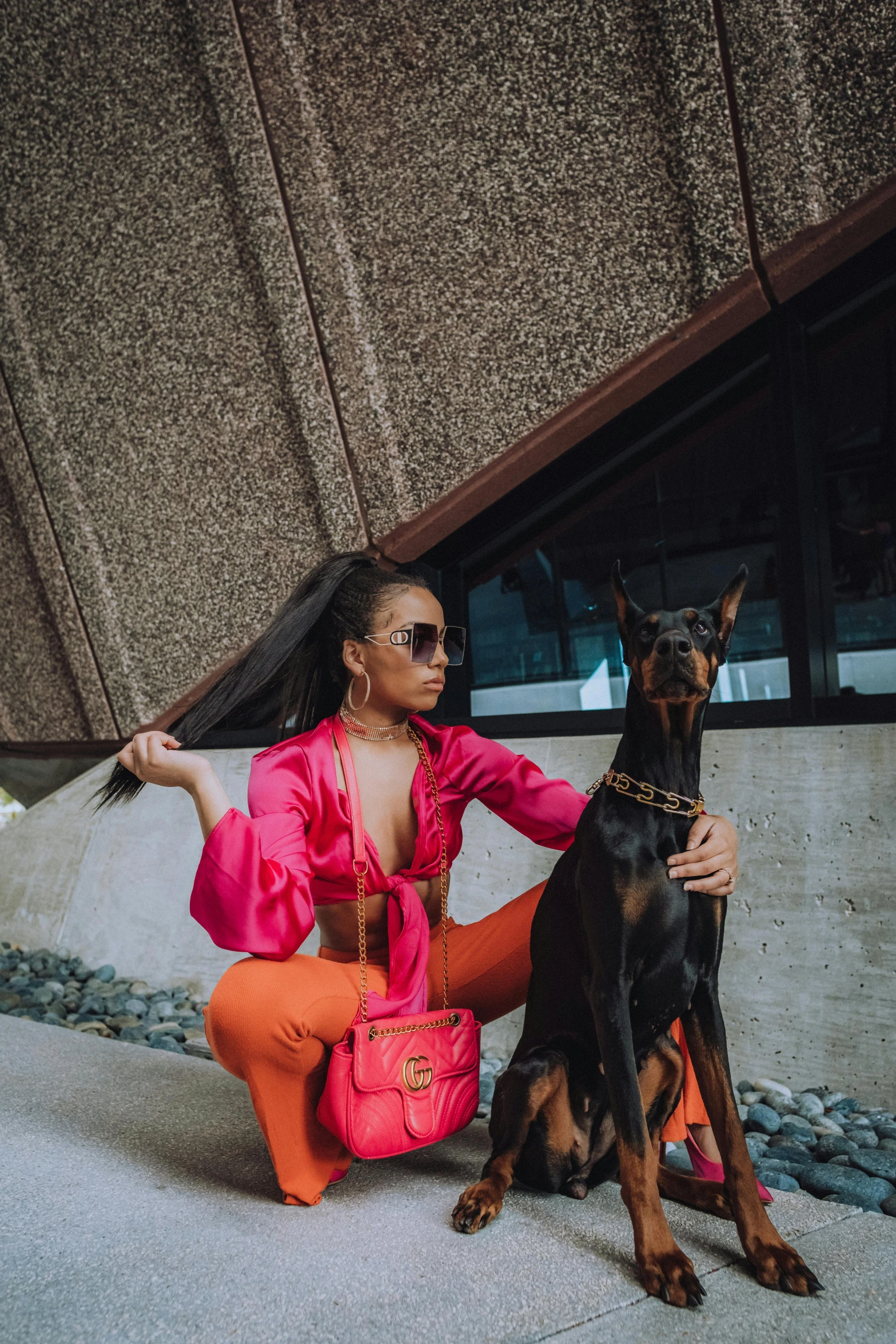 a woman poses with her dog on the sidewalk