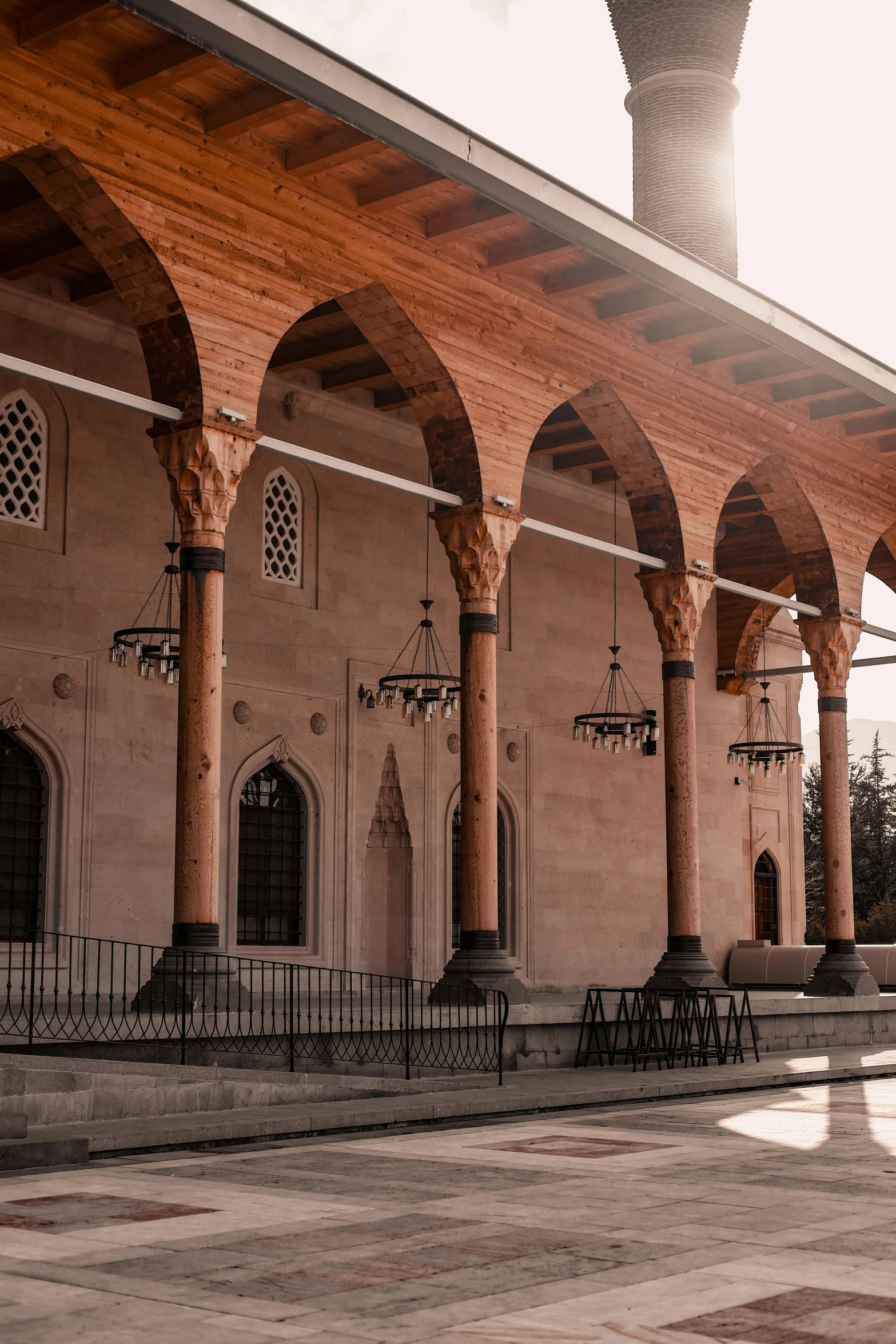 an ornate building with pillars, arched windows and chairs on the outside of it